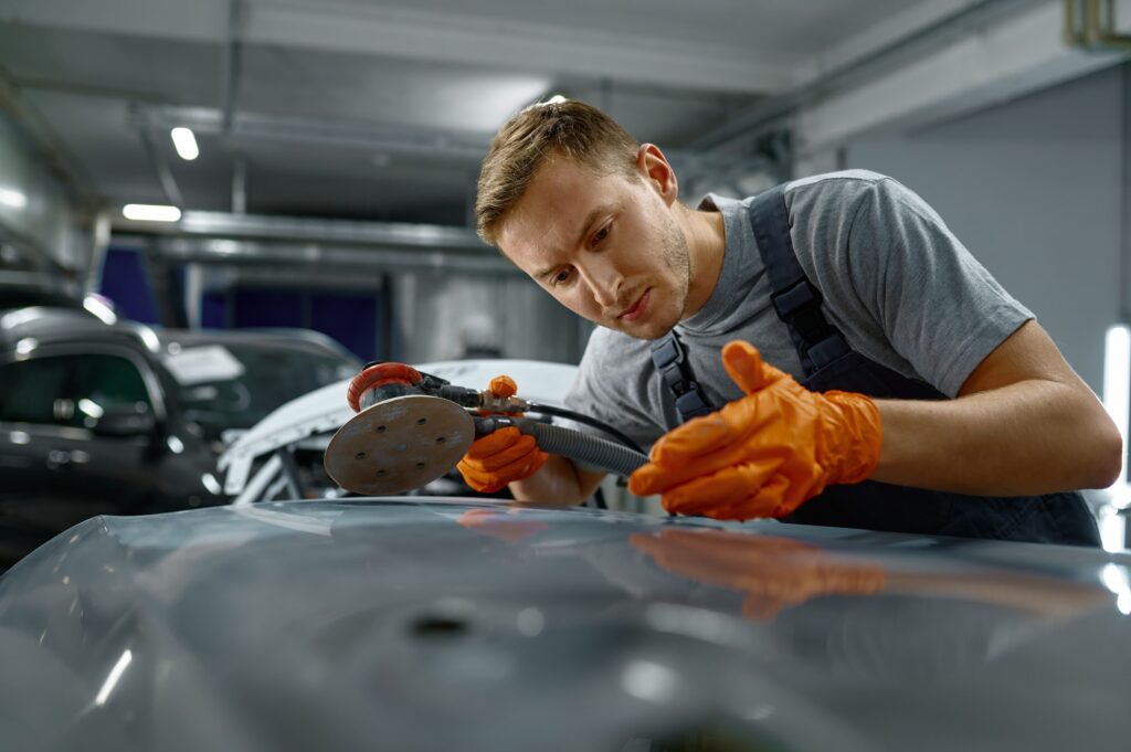 Man using grinder to remove car rust