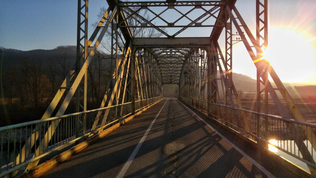 Afternoon sunlight shining through iron construction of a road bridge.