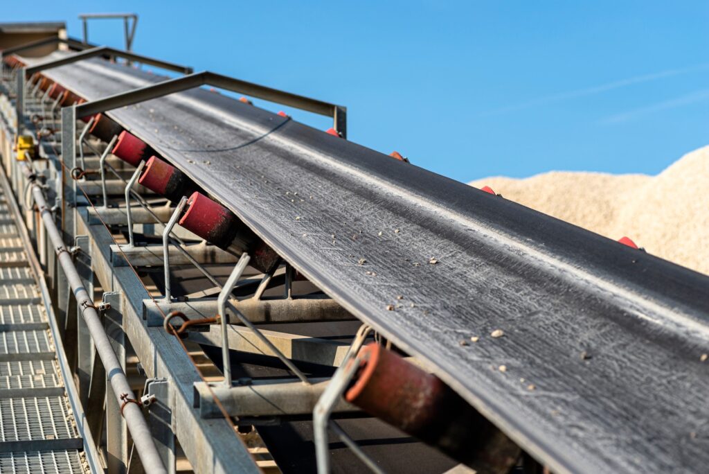 Close-up shot of the conveyor belt in the concrete plant with transport rollers, visible metal stair