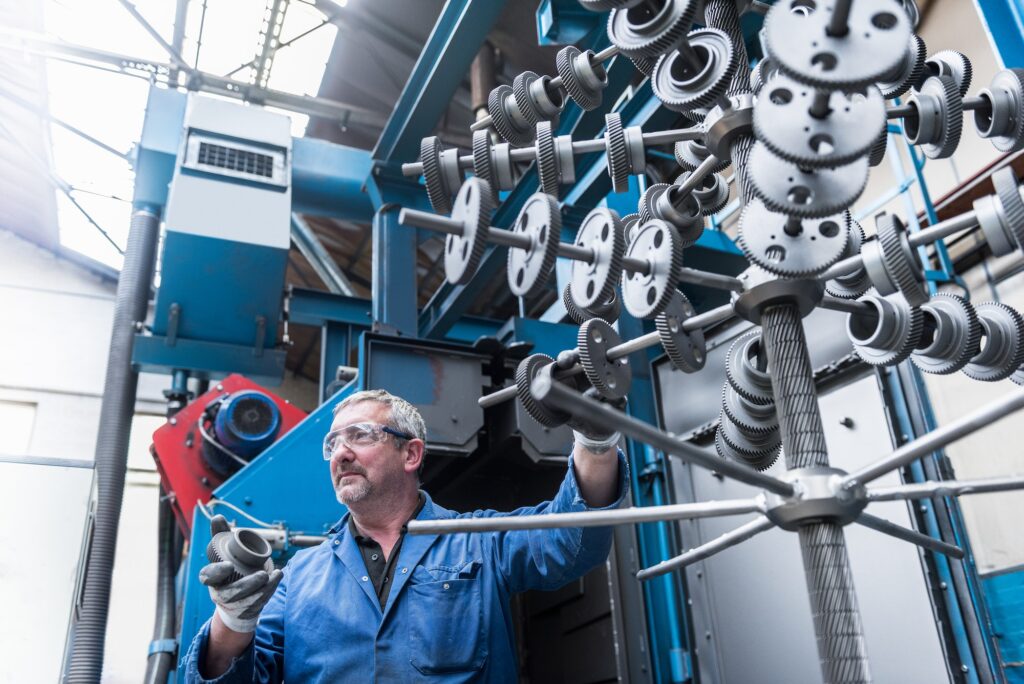 Engineer with shot blasted gear wheels in engineering factory