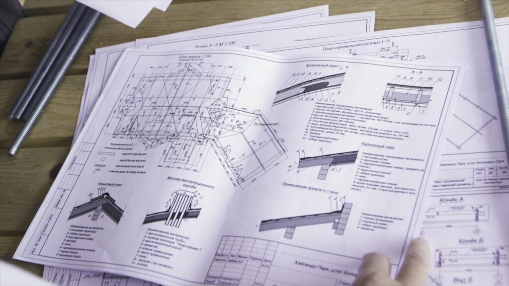 Close up for hands of workers at a factory looking through technical drawings. Blueprints with