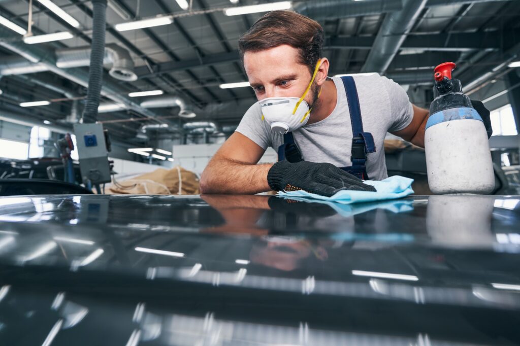 Worker checking an automobile surface after cleaning