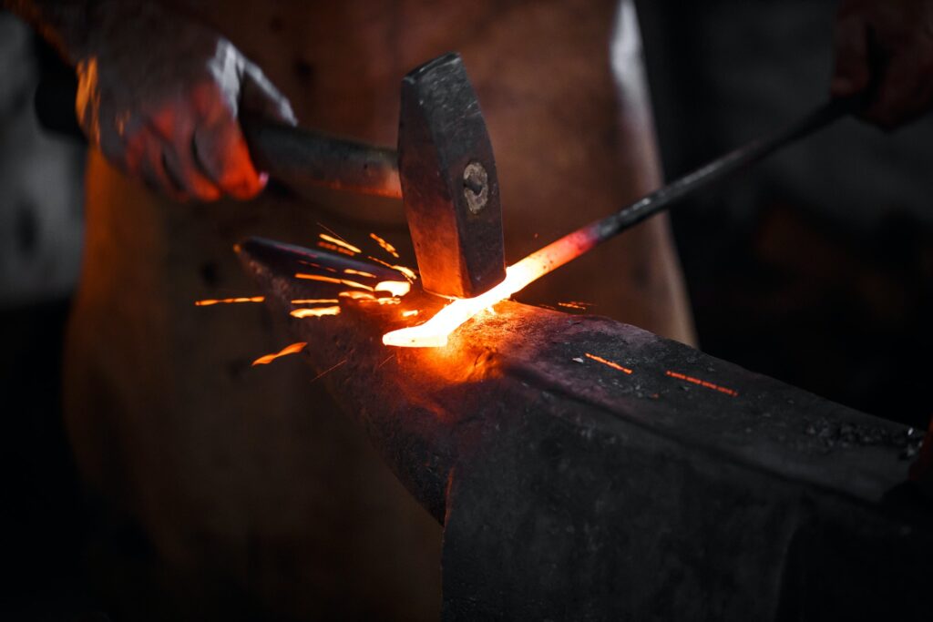 Blacksmith manually forging the molten metal